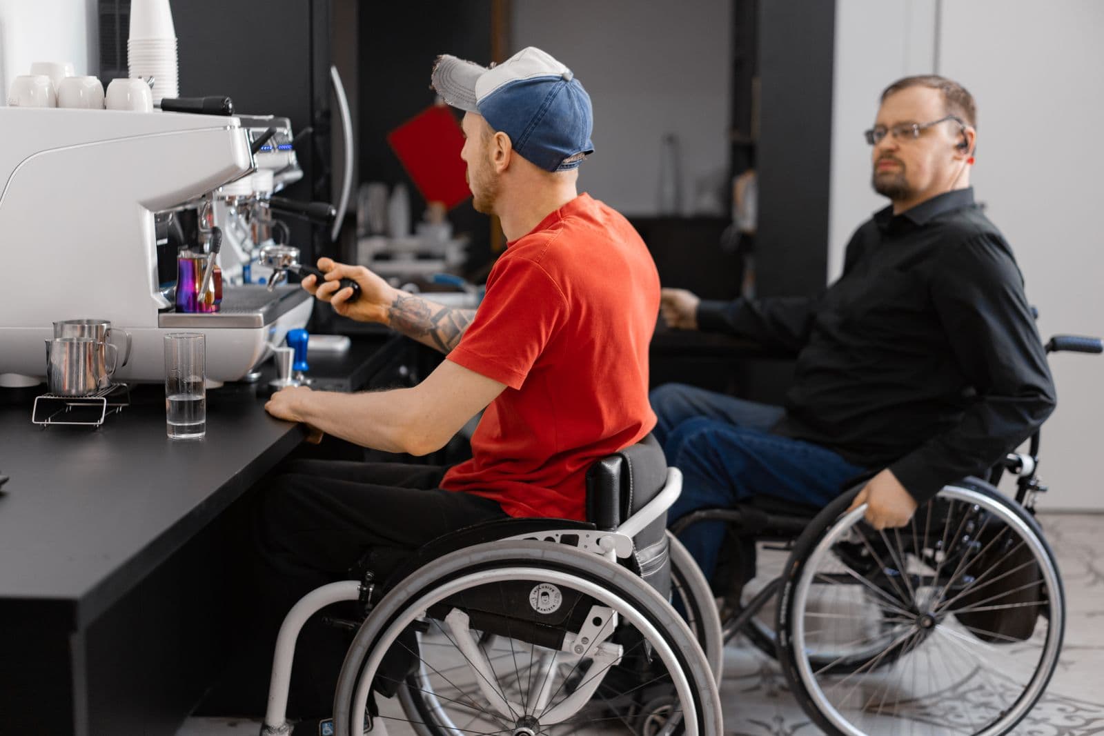 Two coworkers who use wheelchairs working together at a coffee shop